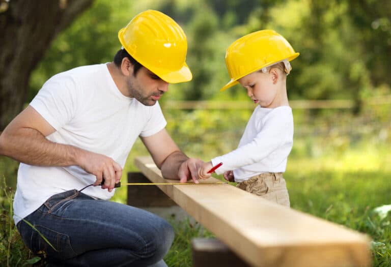 Little boy and father measuring wood to cut