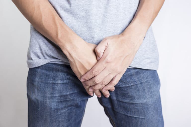 Man covering groin with hands