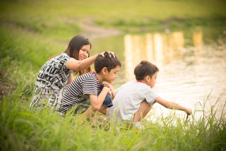 Single mother with two sons by a pond