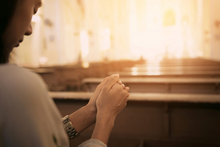 Woman praying in church pew