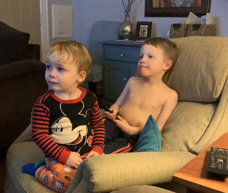 Two little boys sitting on a recliner, color photo