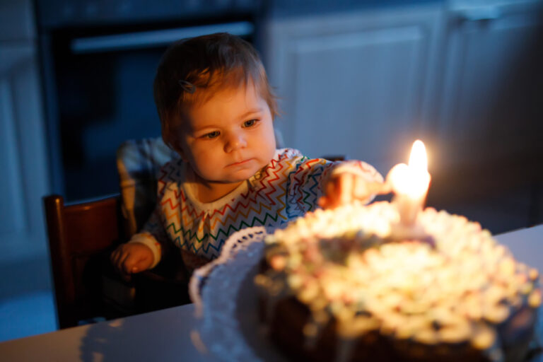 Toddler with first birthday cake and candle