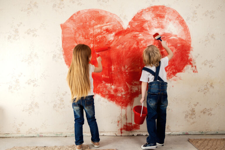 Kids painting a red hart on wall