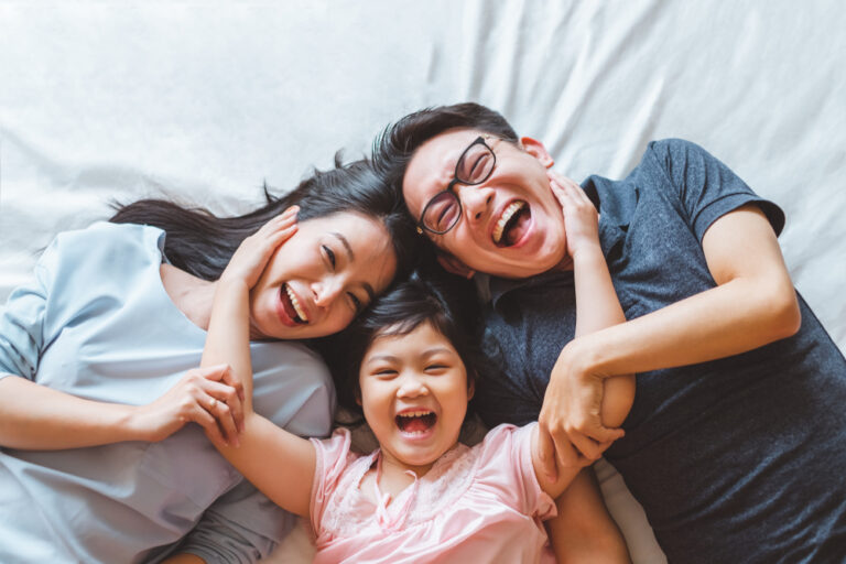 Family laughing together on bed at home
