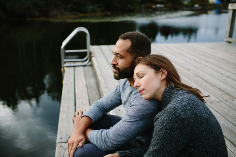 Man and woman sitting on end of dock by water