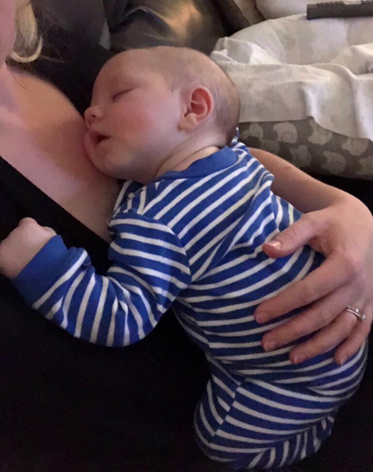 Baby sleeping on his mother's chest, color photo
