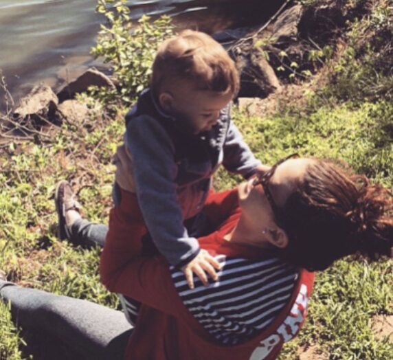 Mom holding little boy near lake edge, color photo