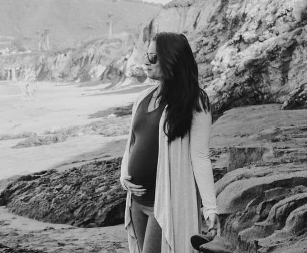 Black and white image of pregnant woman on beach