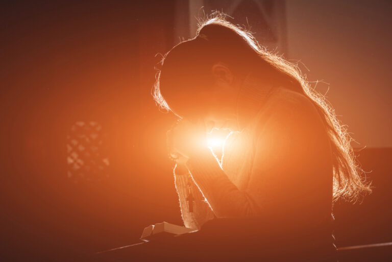 Praying woman in sunlight at church