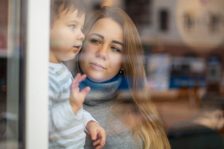 Mom holding toddler looking out window