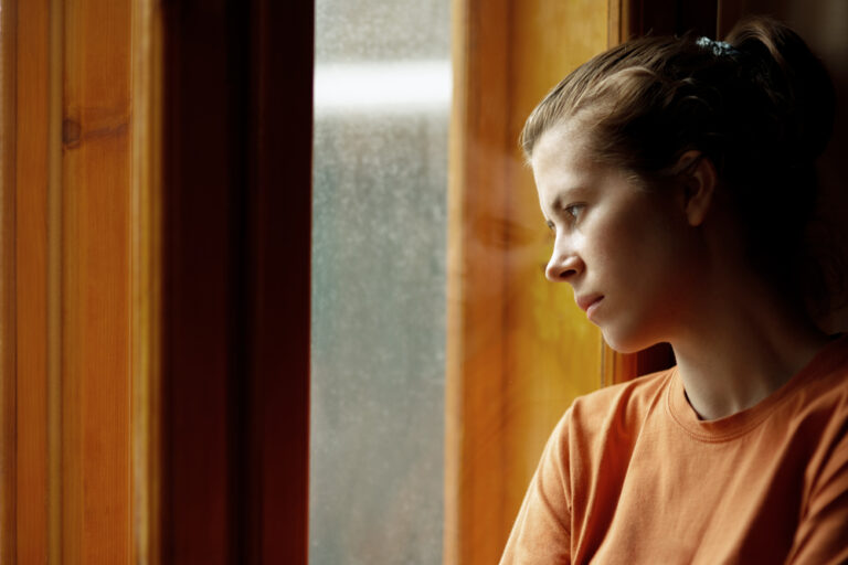 Woman looking out window sad
