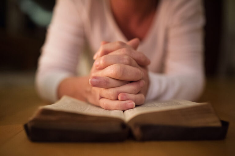 Woman praying with open Bible