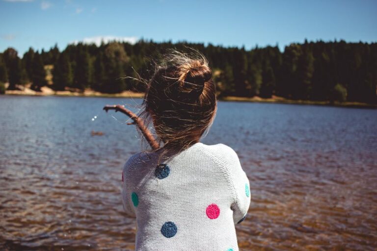 Back view of little girl standing by lake