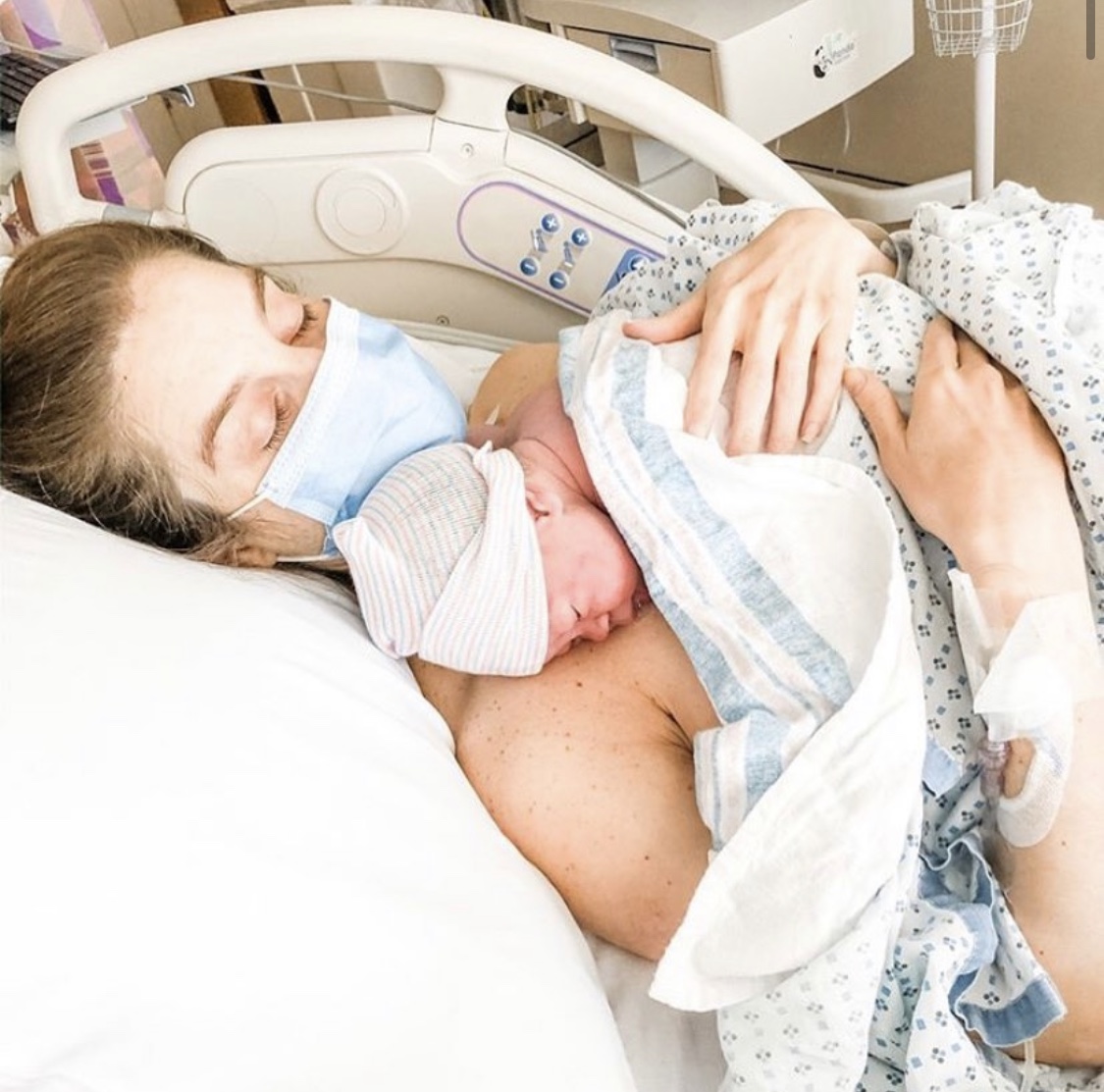 Mother wearing mask with newborn in hospital, color photo