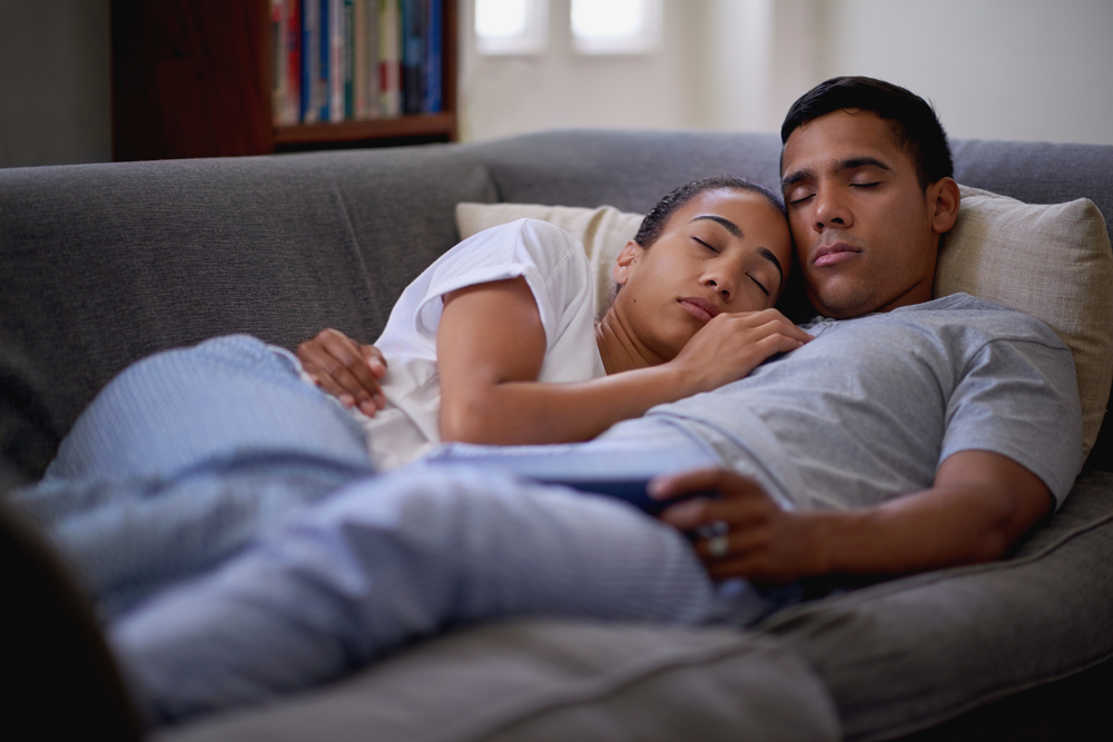 Gay Couple Embracing While Relaxing On Sofa Stock Photo