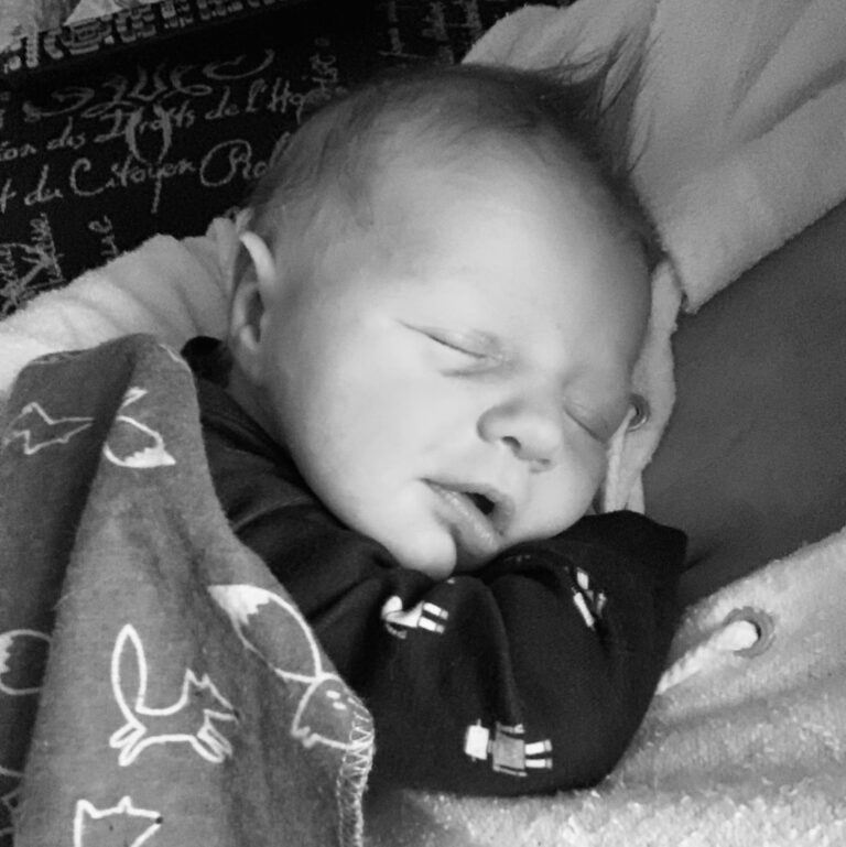 Newborn asleep on mother, black-and-white photo