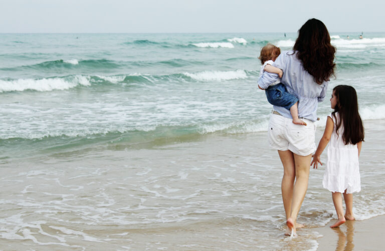 Mom walking on beach with children
