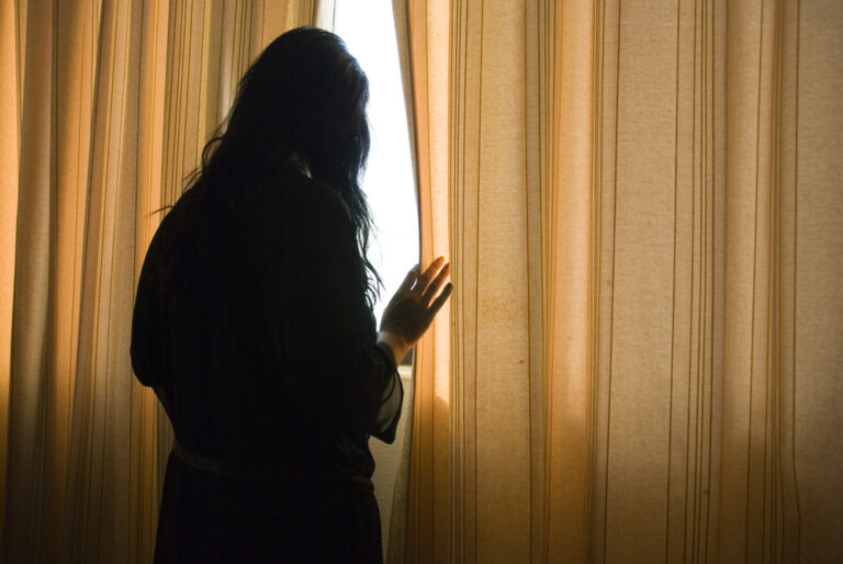 Woman looking out window at home