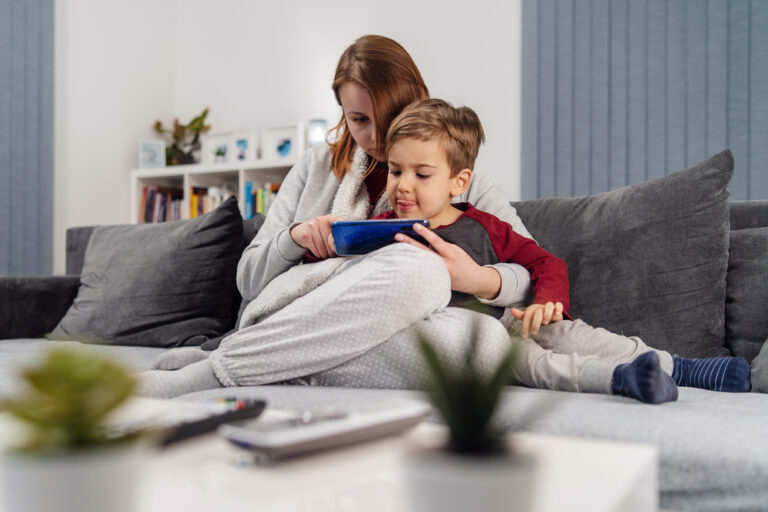 Mom with young son on couch watching device