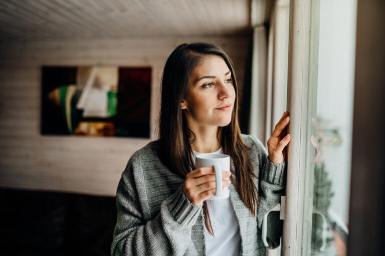 Woman with coffee cup looking out window
