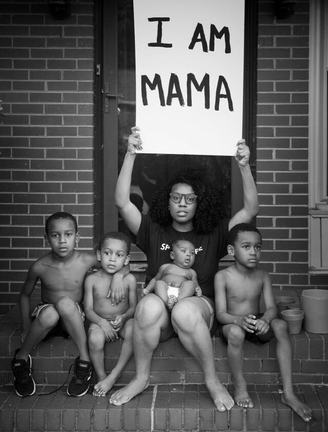 Black mother with sons holding "I am mama" sign