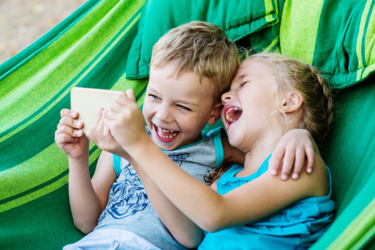 Two kids laughing together in hammock