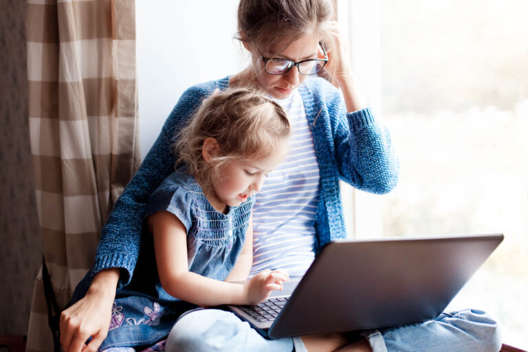 Mom working on computer with daughter at side