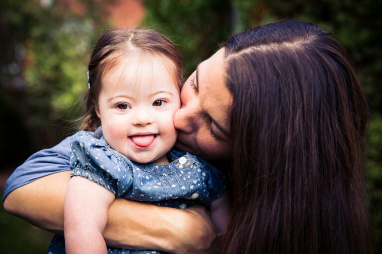 Mother kissing daughter with Down syndrome