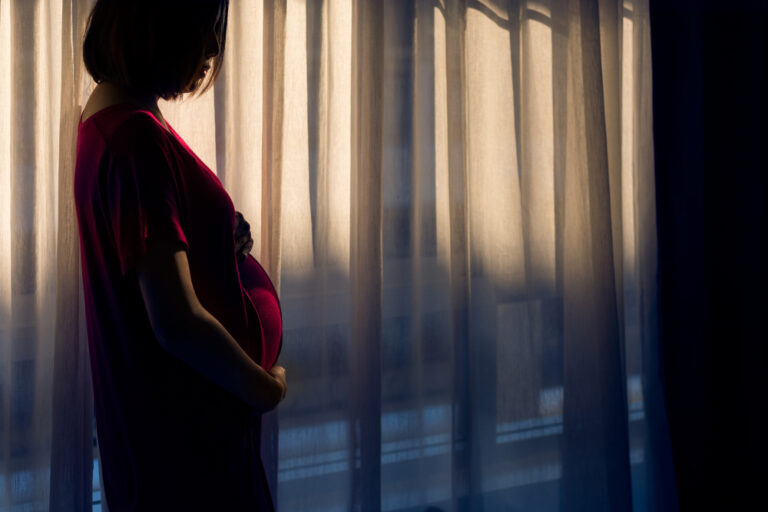 Pregnant woman by dark window