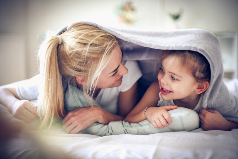 Mother and daughter under blanket