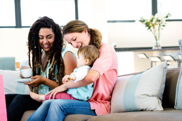 Two moms holding baby on couch
