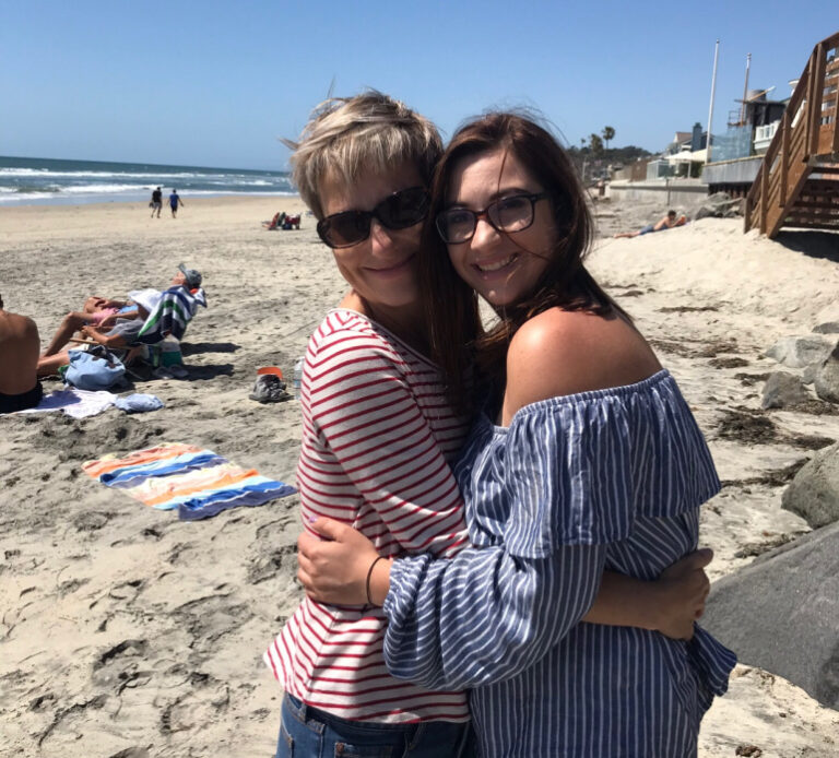 Two women hugging on beach, color photo