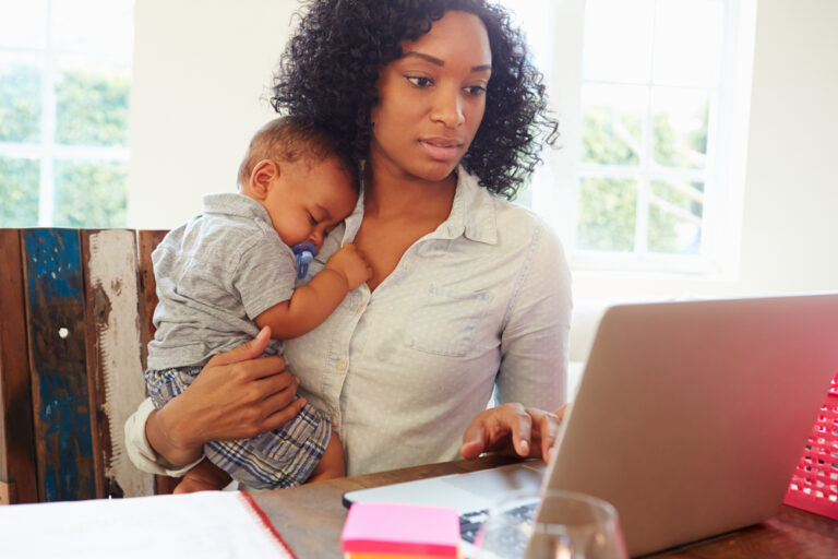Woman holding baby working on computer