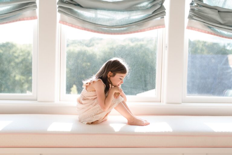 Little girl sitting on window seat, color photo