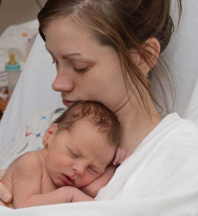 Mother holding newborn in hospital, color photo
