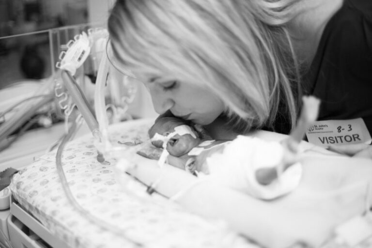 Mom kissing baby in NICU
