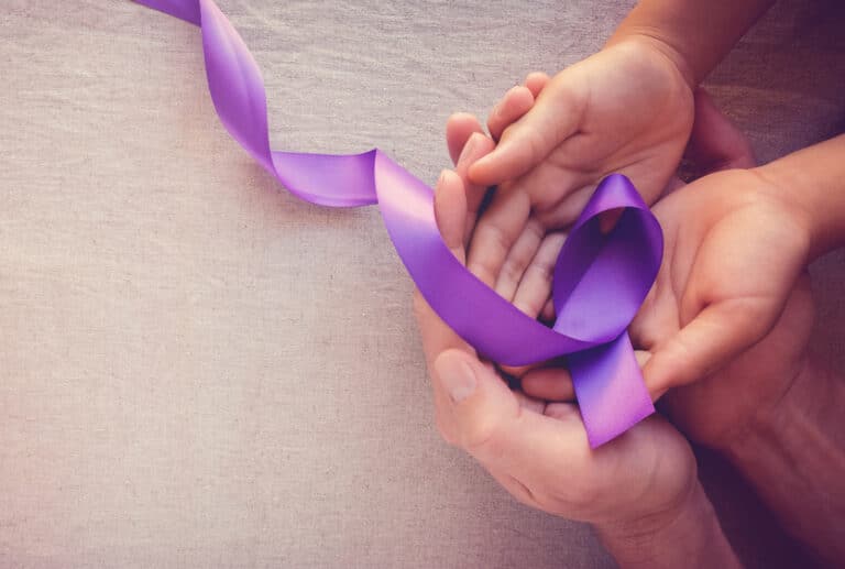 Hands holding purple ribbon