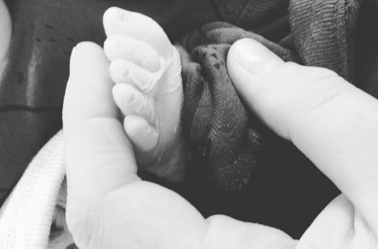 woman's hand holding baby foot