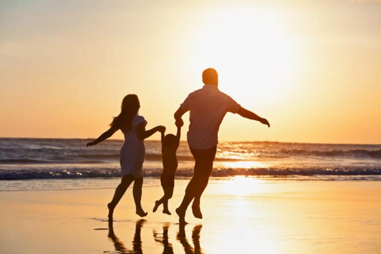 Family running on beach at sunset