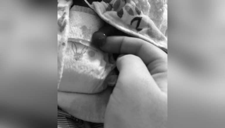 Mother holding hand of preemie, black-and-white photo
