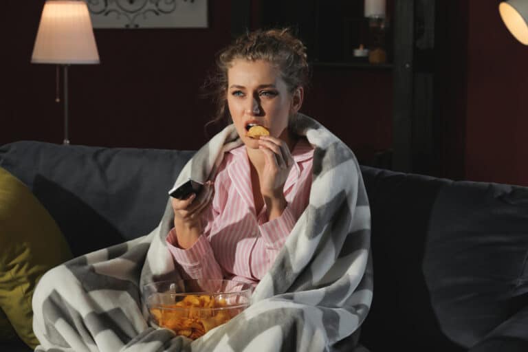 Woman watching TV eating snacks