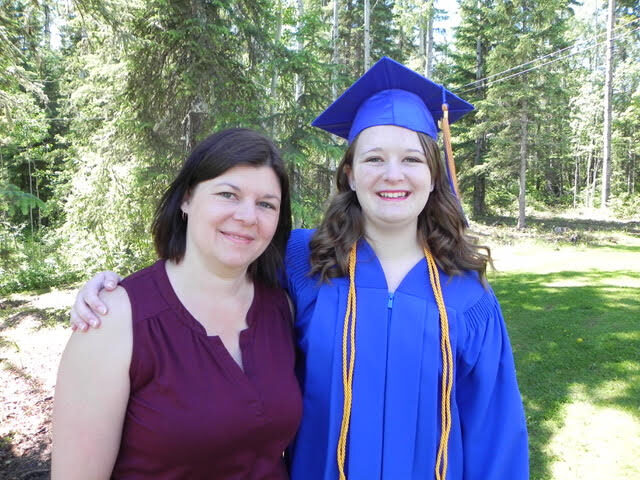 Mother standing with high school graduate, color photo