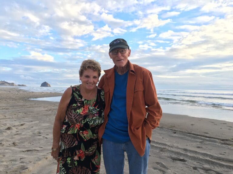 Older couple standing on beach together, color photo
