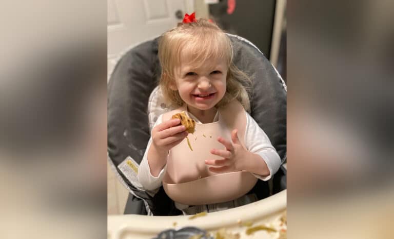 Smiling little girl sitting in high chair, color photo