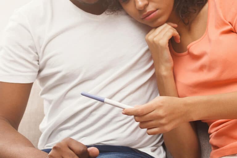 Man and woman looking sadly at pregnancy test