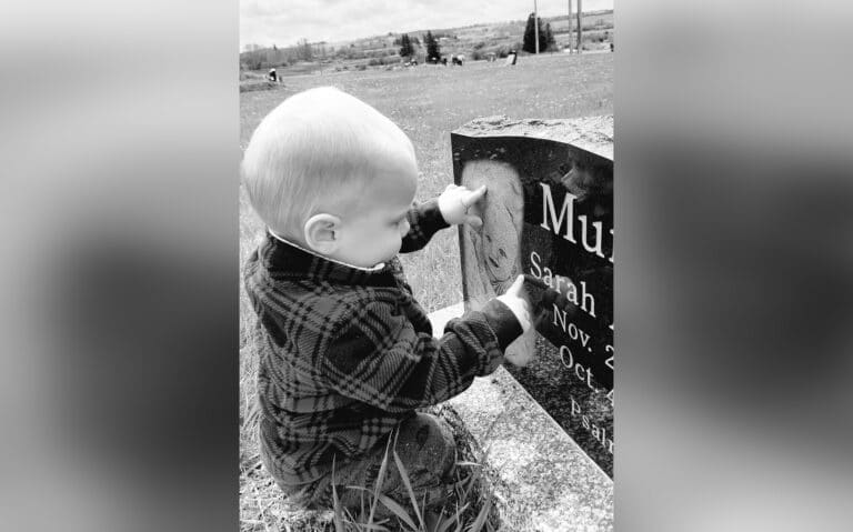 Toddler next to baby sister's grave, black-and-white photo
