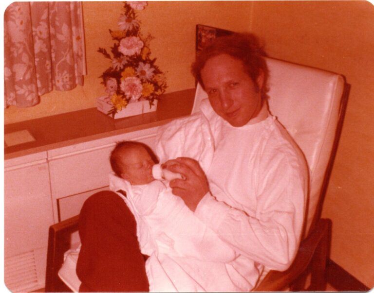 Father holding infant, old color photo