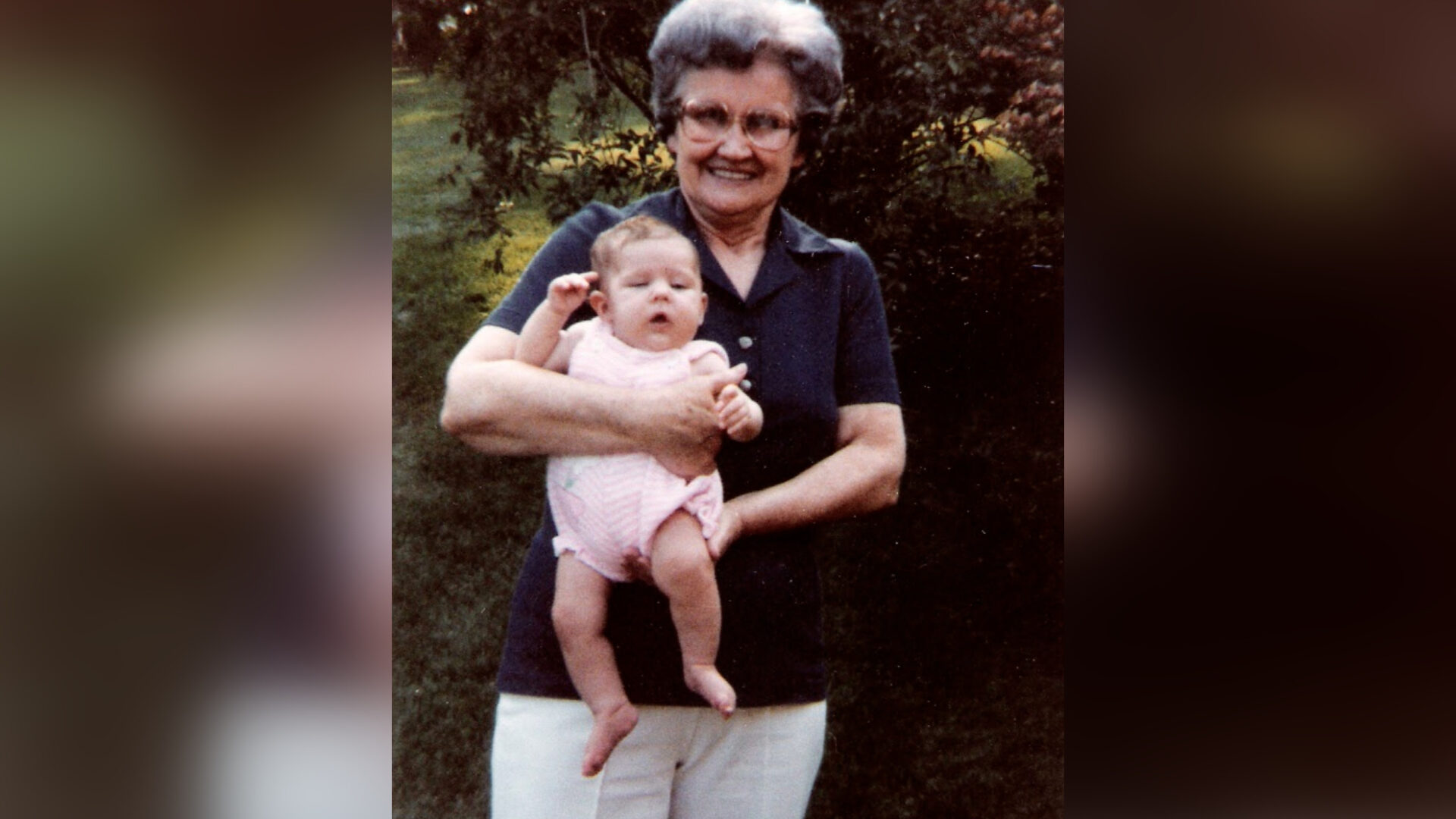 Grandmother holding infant, color photo
