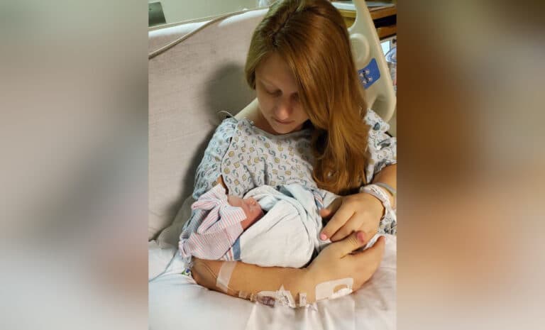 Mother holding newborn daughter in hospital, color photo
