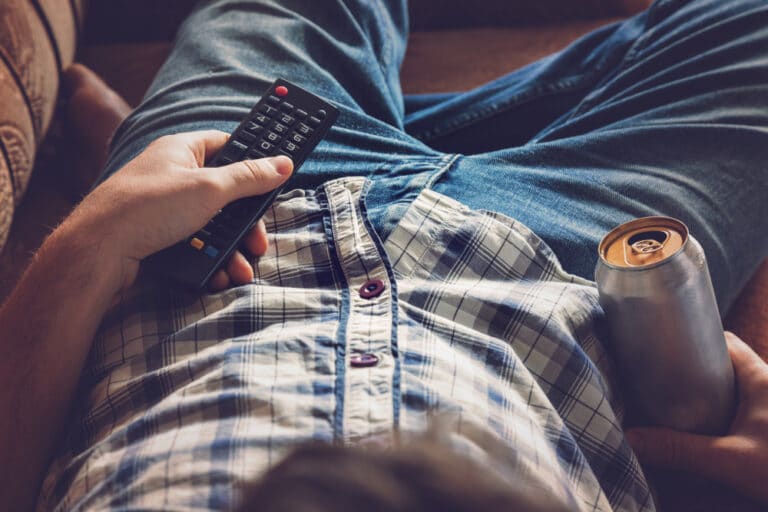 Man holding beer and remote